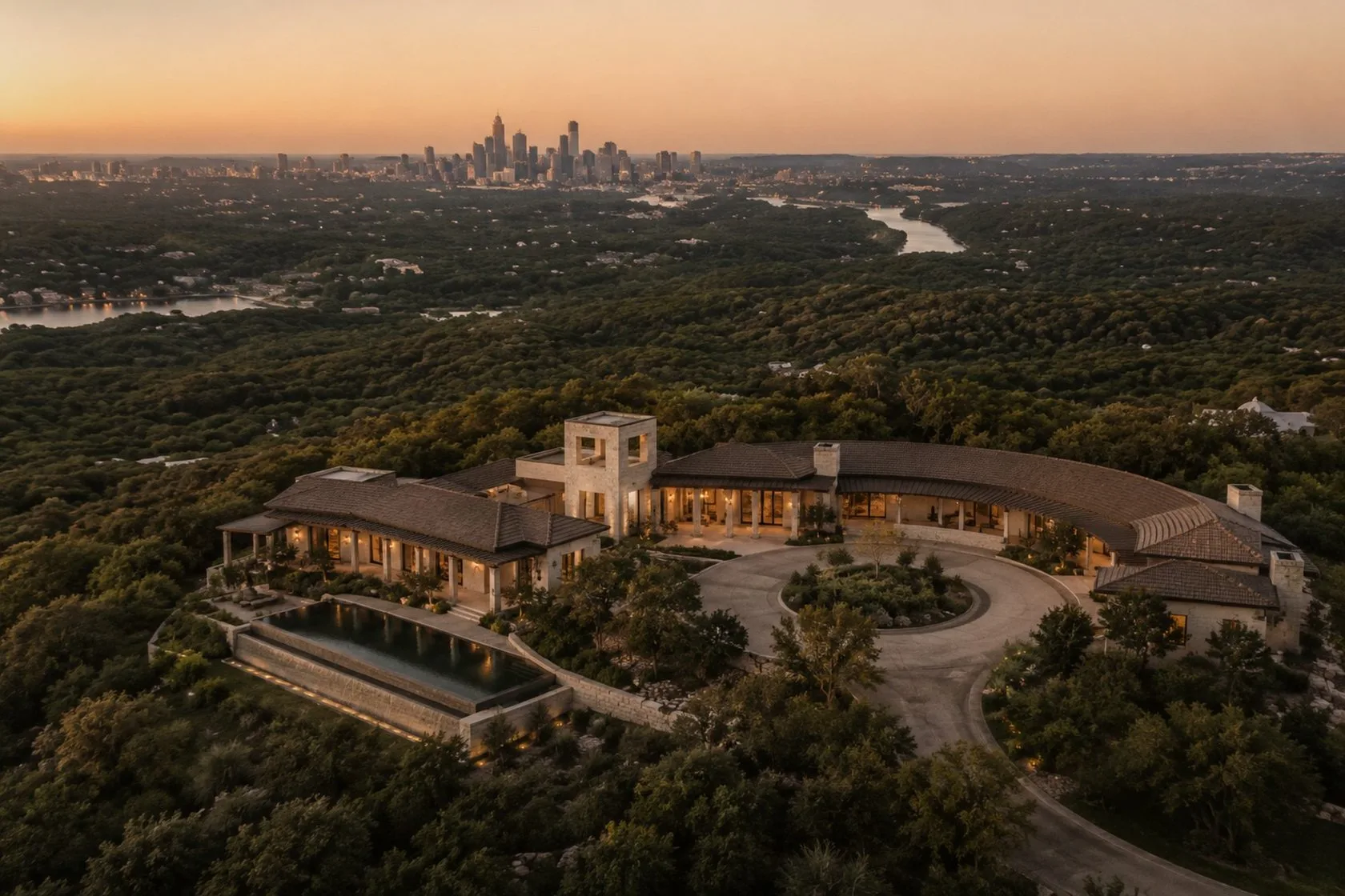 Aerial view of a hilltop estate above a forested valley at dusk